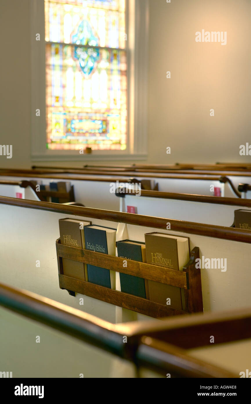 Bancs d'église bibles psautiers et vitrail dans l'orientation verticale Banque D'Images