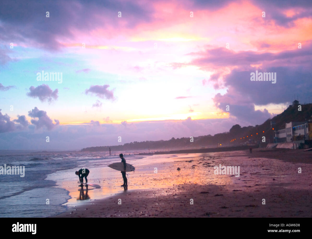 Les surfeurs surfer surf board BOURNEMOUTH Dorset dans la soirée les poussettes sur la plage mer ciel maison de vacances brochure Banque D'Images