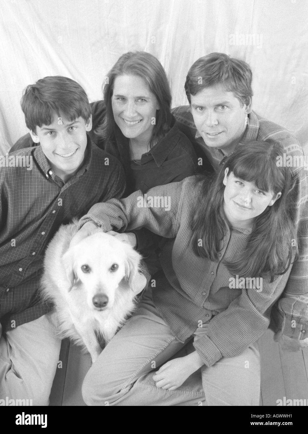Photo de groupe en noir et blanc d'une famille de quatre personnes de race blanche assis avec leur chien : mère, père, et préadolescent son fils et sa fille. Banque D'Images