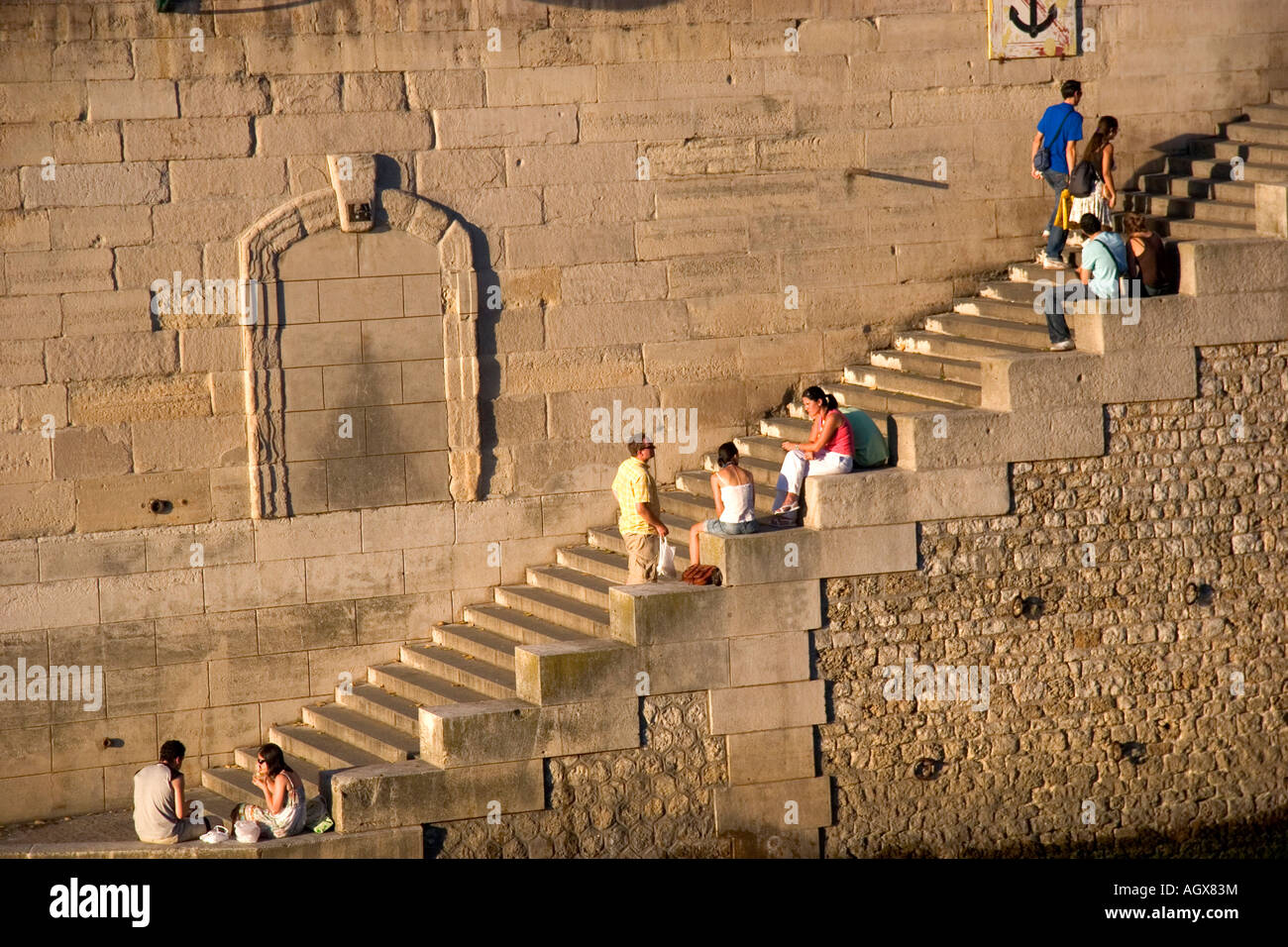 Les gens s'assoient sur les marches de pierre le long de la Seine à Paris France Banque D'Images