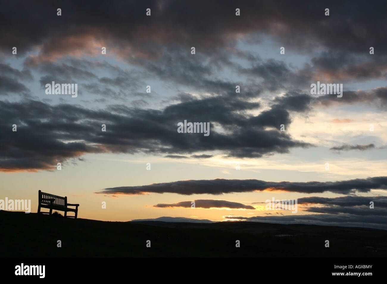 Un banc sur une colline au coucher du soleil Banque D'Images
