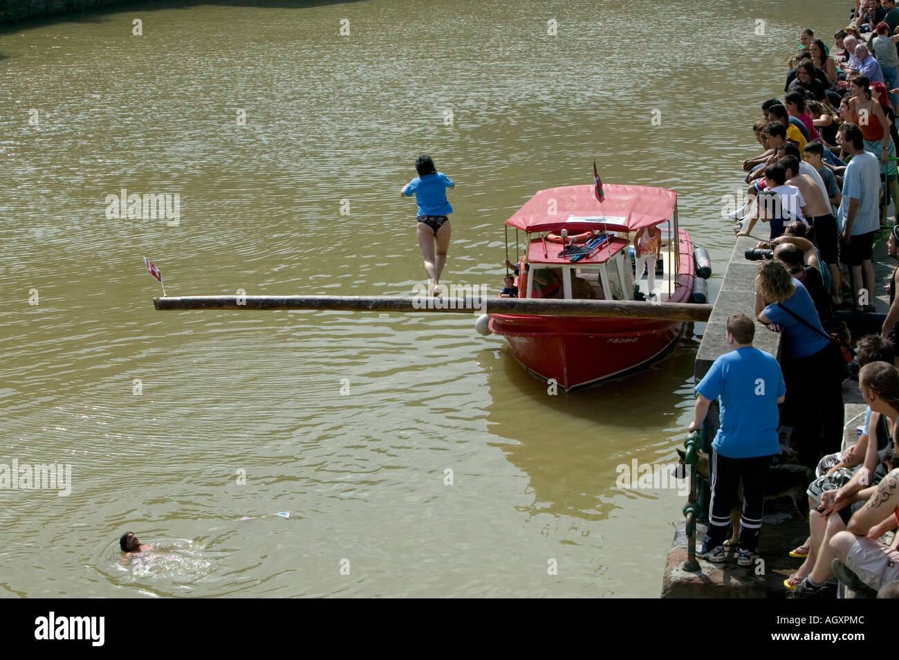 Femme en équilibre sur un mât de cocagne sur la rivière Nervión en face de foule pendant la Cucaña fiesta Bilbao Pays basque Espagne Banque D'Images