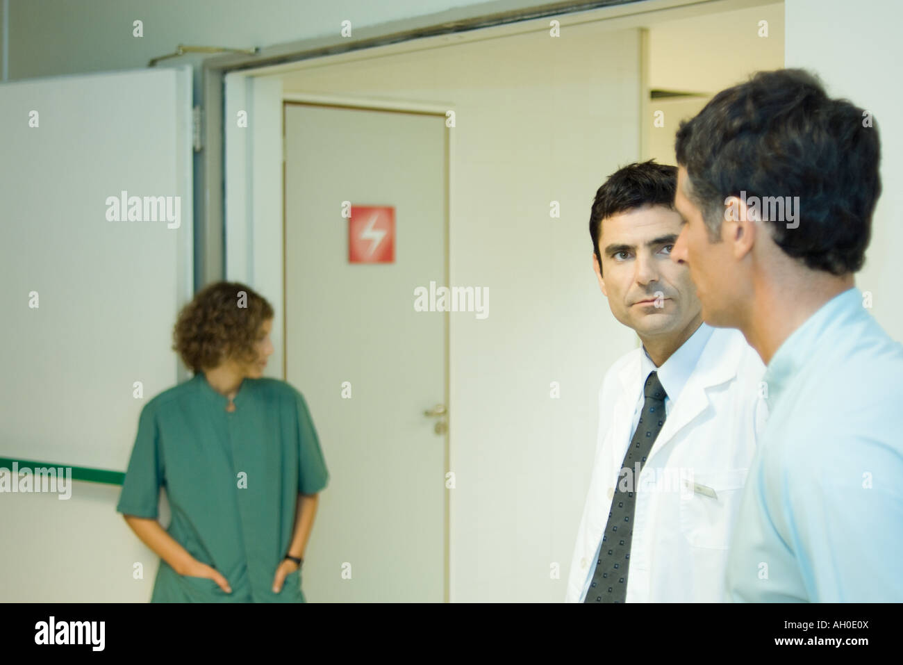 Homme debout avec un médecin à l'hôpital, side view, woman in background Banque D'Images