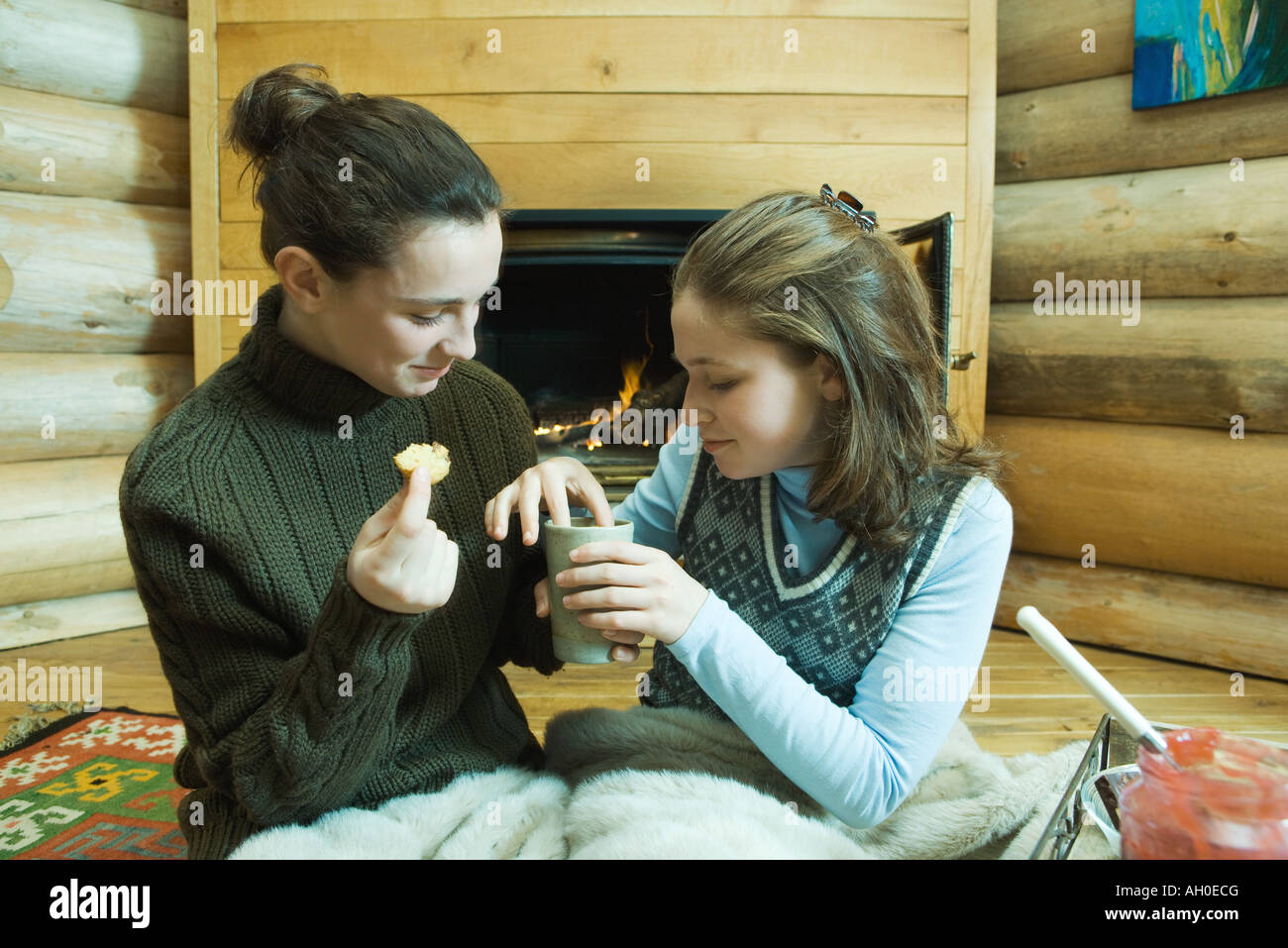 Deux adolescentes assis par cheminée, snack-partage Banque D'Images