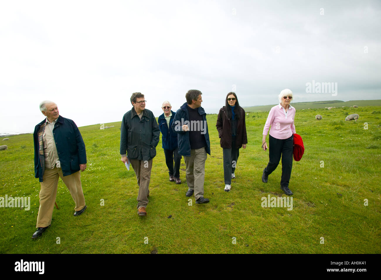 Les touristes étant illustré autour de Château de Dunstanburgh Northumberland par un guide du patrimoine français Banque D'Images