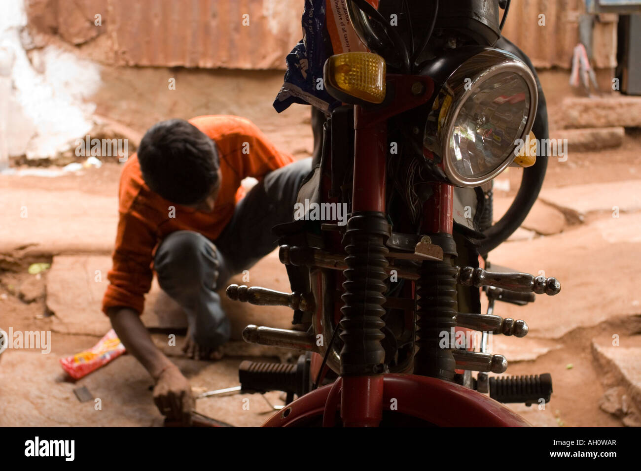 Jeune Indien la fixation d'un pneu à plat sur un scooter dans un magasin de vélo à Hospet Inde Banque D'Images