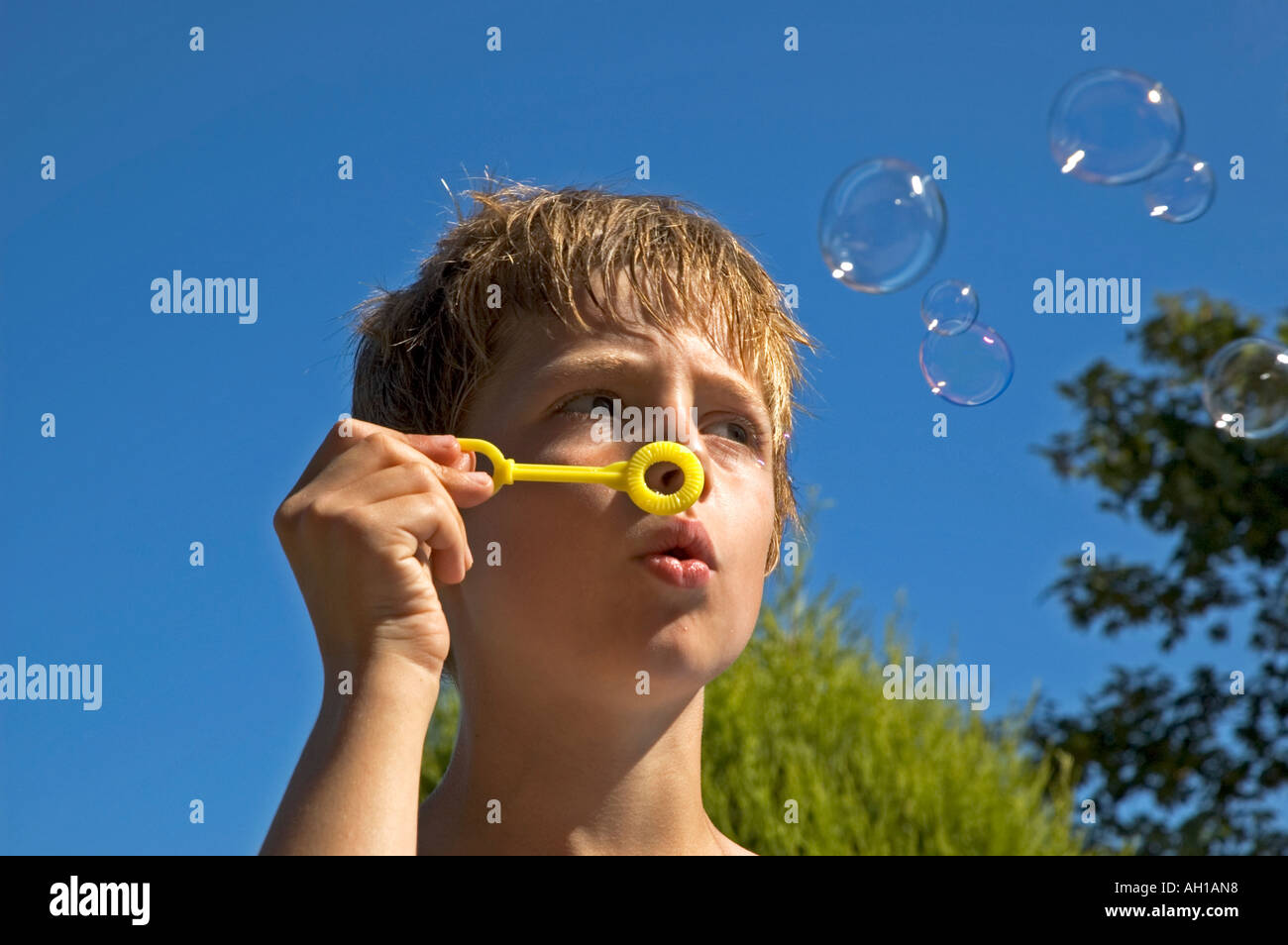 Un jeune garçon s'amusant faire des bulles à l'extérieur sur summers day Banque D'Images