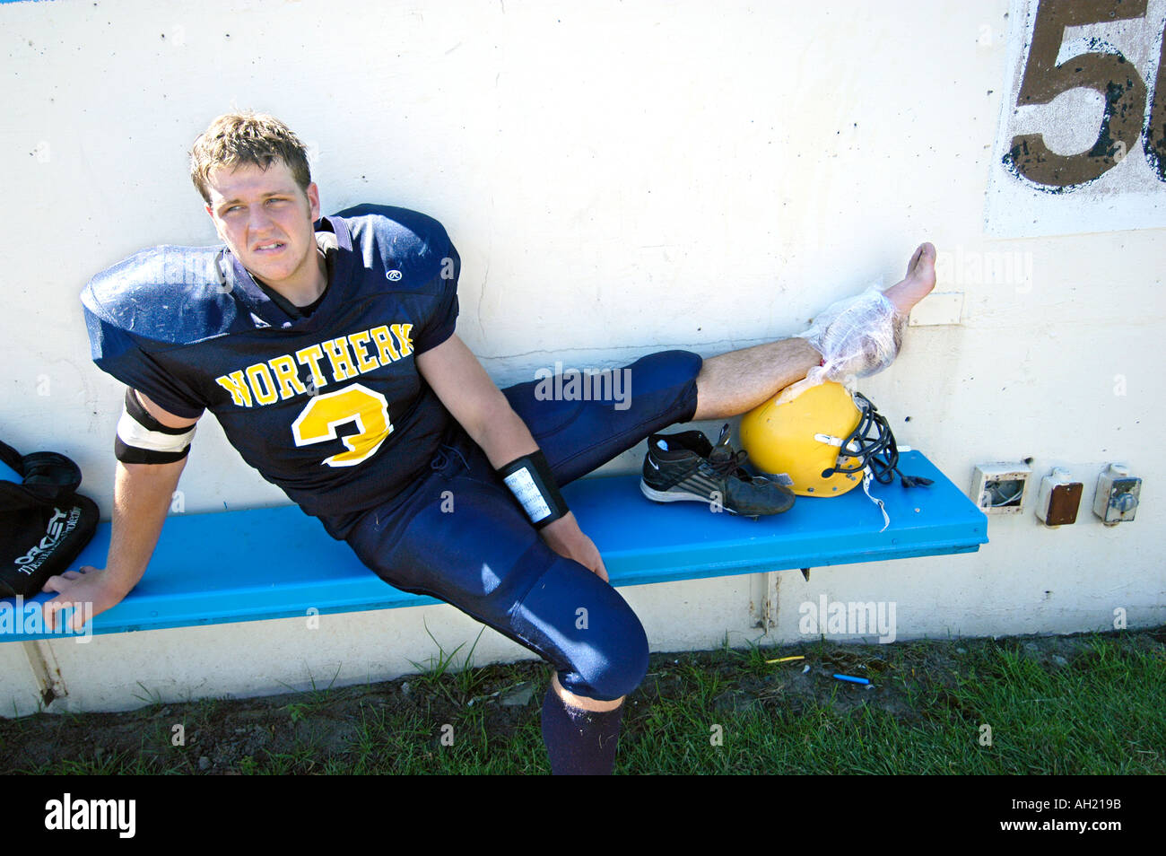 Blessé High School Football Player avec de la glace sur l'entorse de cheville blessée Banque D'Images
