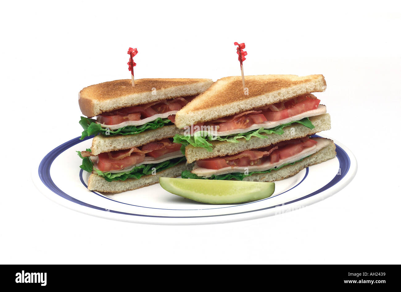 Club sandwich avec un cornichon sur la plaque se découpant sur fond blanc Banque D'Images