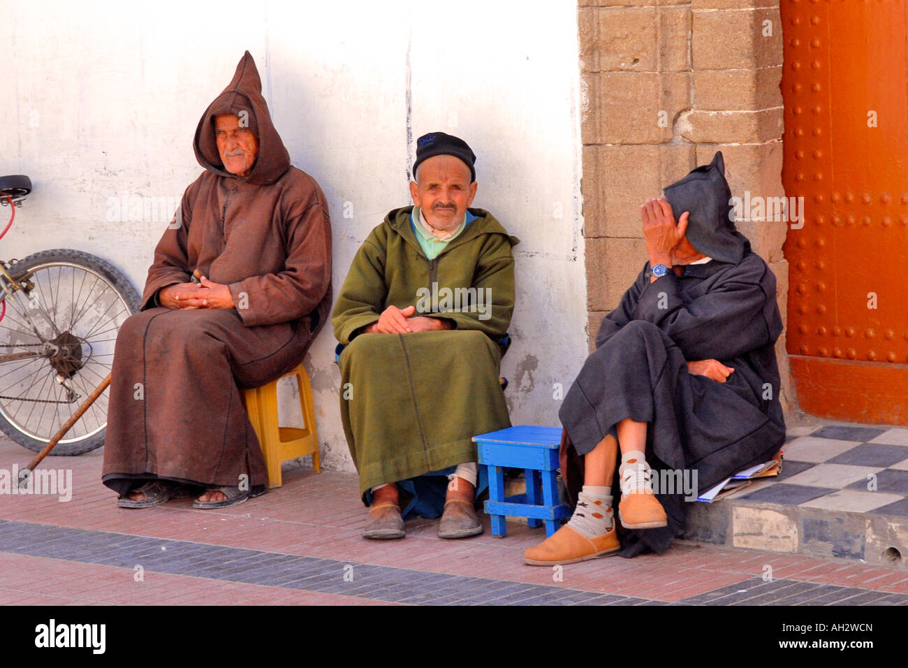 Maroc , Marrakech , Médina , scène typiquement africaine de trois hommes âgés en thoubs assis dans un coin à l'ombre du chat de la chaussée Banque D'Images