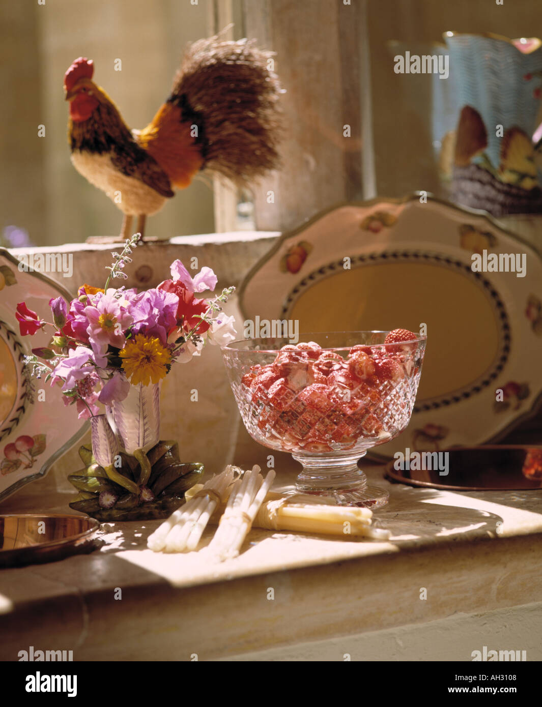 Still-Life de fraises dans cut-vase en verre avec petit bouquet de fleurs dans un vase d'été ci-dessous coquelet ornement sur rebord de la Banque D'Images