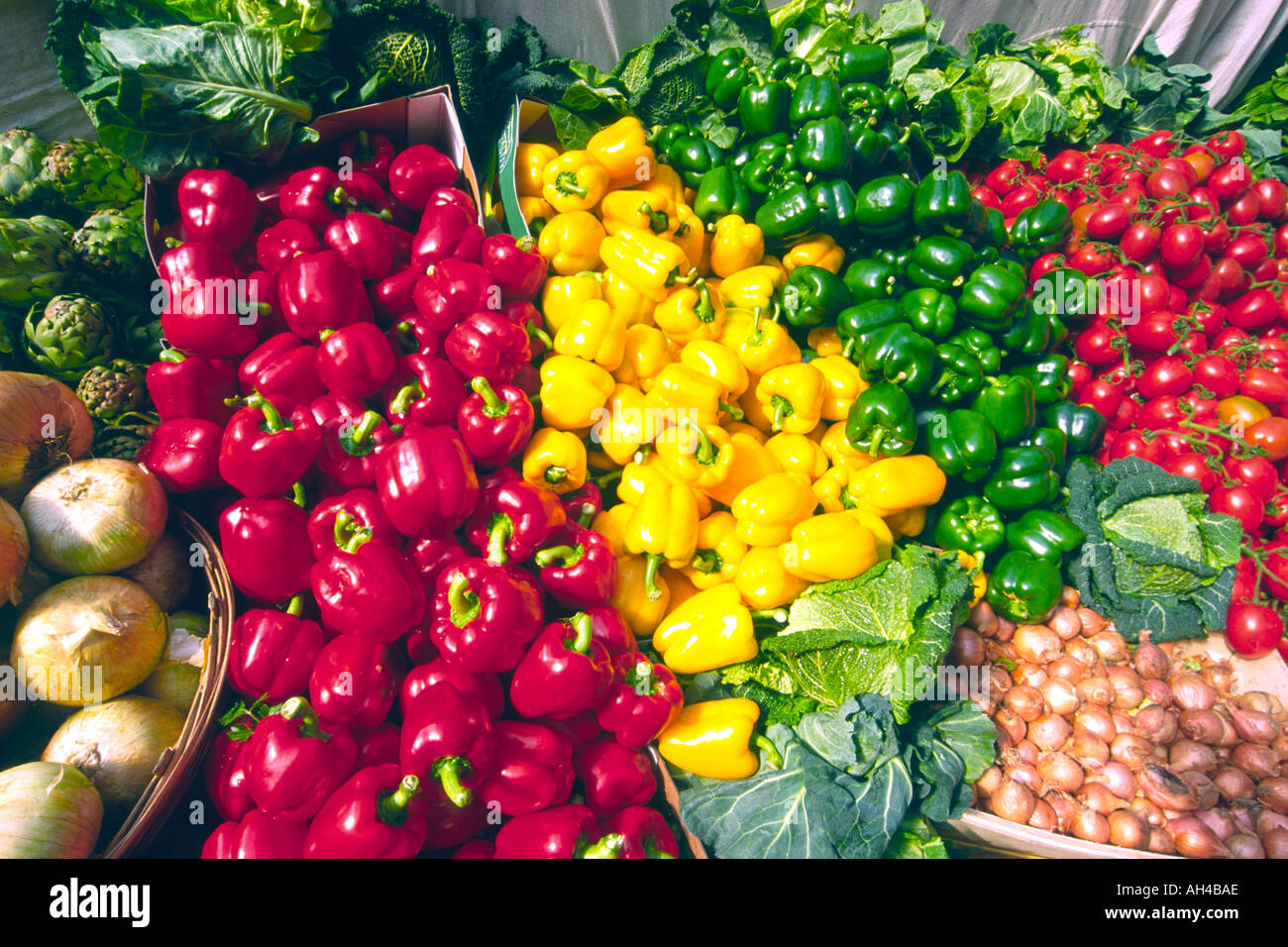 Légumes variés, y compris les oignons, tomates, choux et poivrons rouges, verts et jaunes at a market stall. Banque D'Images
