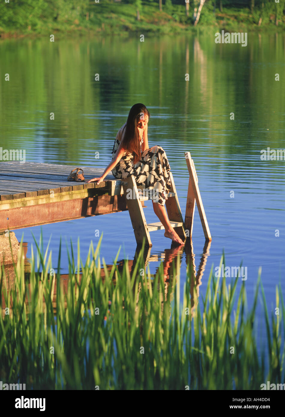 Asian woman sitting on lake pier en été Banque D'Images