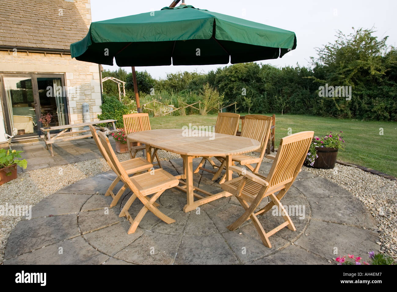 Teak table et chaises de jardin sur terrasse avec grand parasol au-dessus  de Cotswolds UK Photo Stock - Alamy