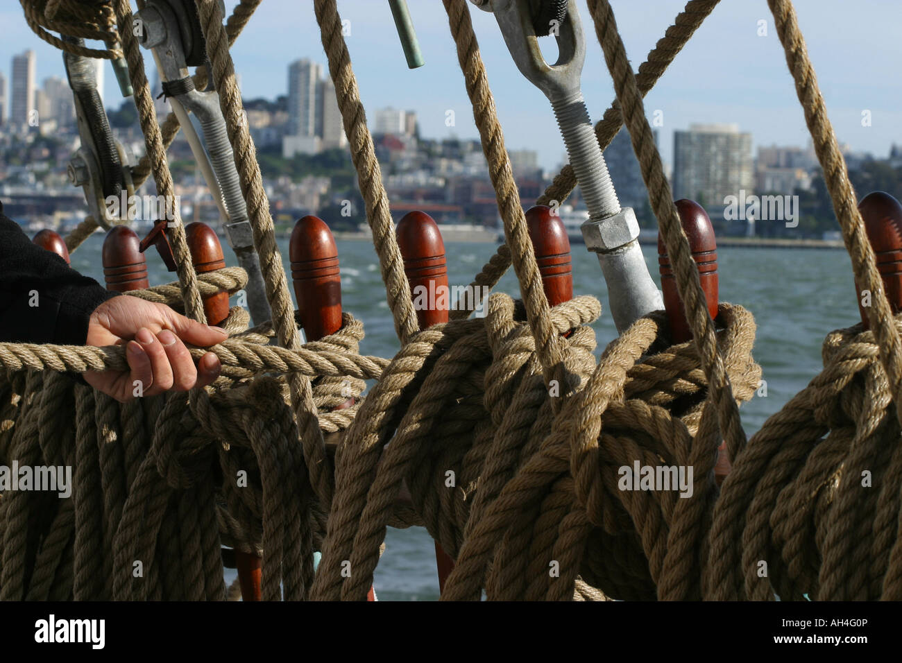 Part d'un marin en tirant sur la ligne autour de la détient à tirer vers le haut la voile dans un grand voilier naviguant sur la baie de San Francisco Banque D'Images