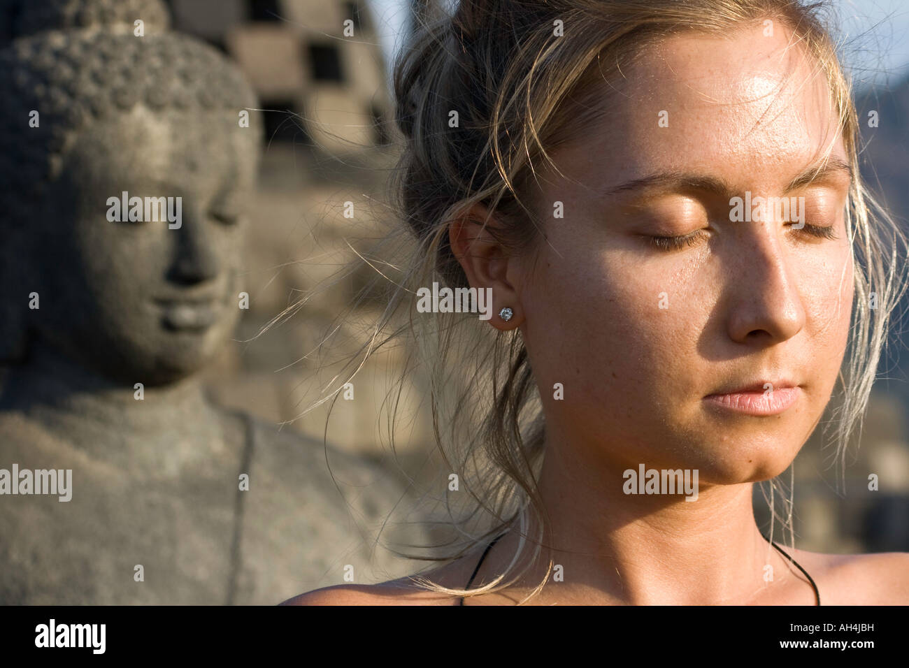 Méditant femme occidentale et statue de Bouddha en pierre Borobudur Indonésie Banque D'Images