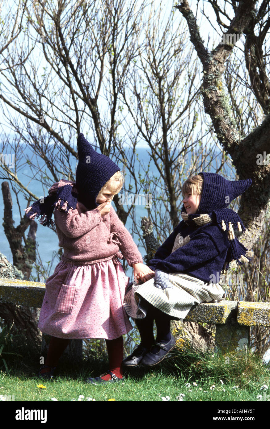 Deux petites filles portant des vêtements d'hiver riant et s'asseyant sur un mur de pierre Banque D'Images