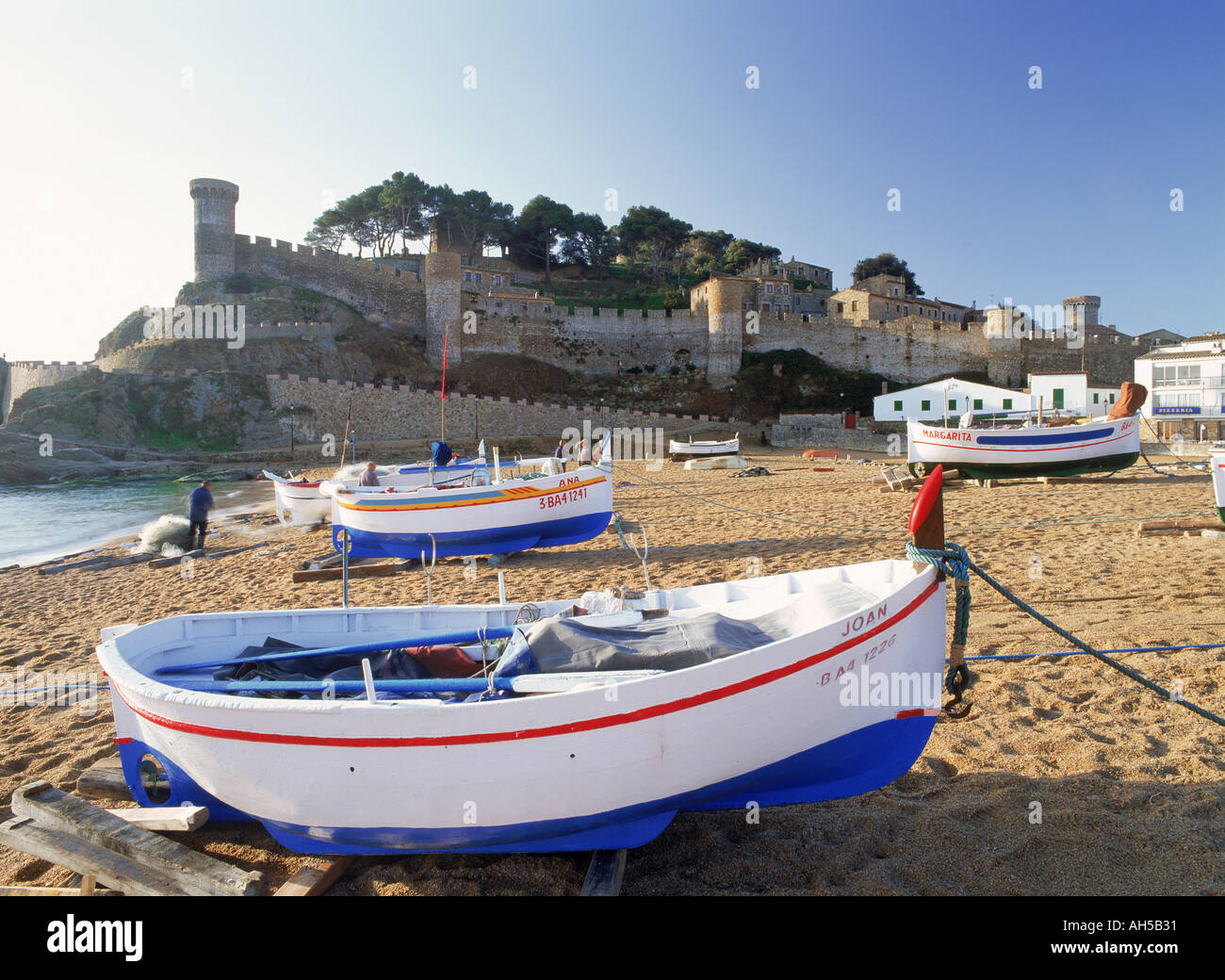 Les bateaux de pêche ci-dessous château à Tossa de Mar en Gérone Province d'Espagne au lever du soleil Banque D'Images