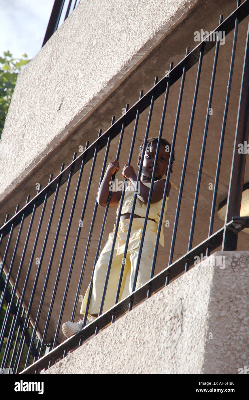 Petit enfant accroché sur les garde-corps du balcon de l'étage supérieur de highrise télévision. Banque D'Images