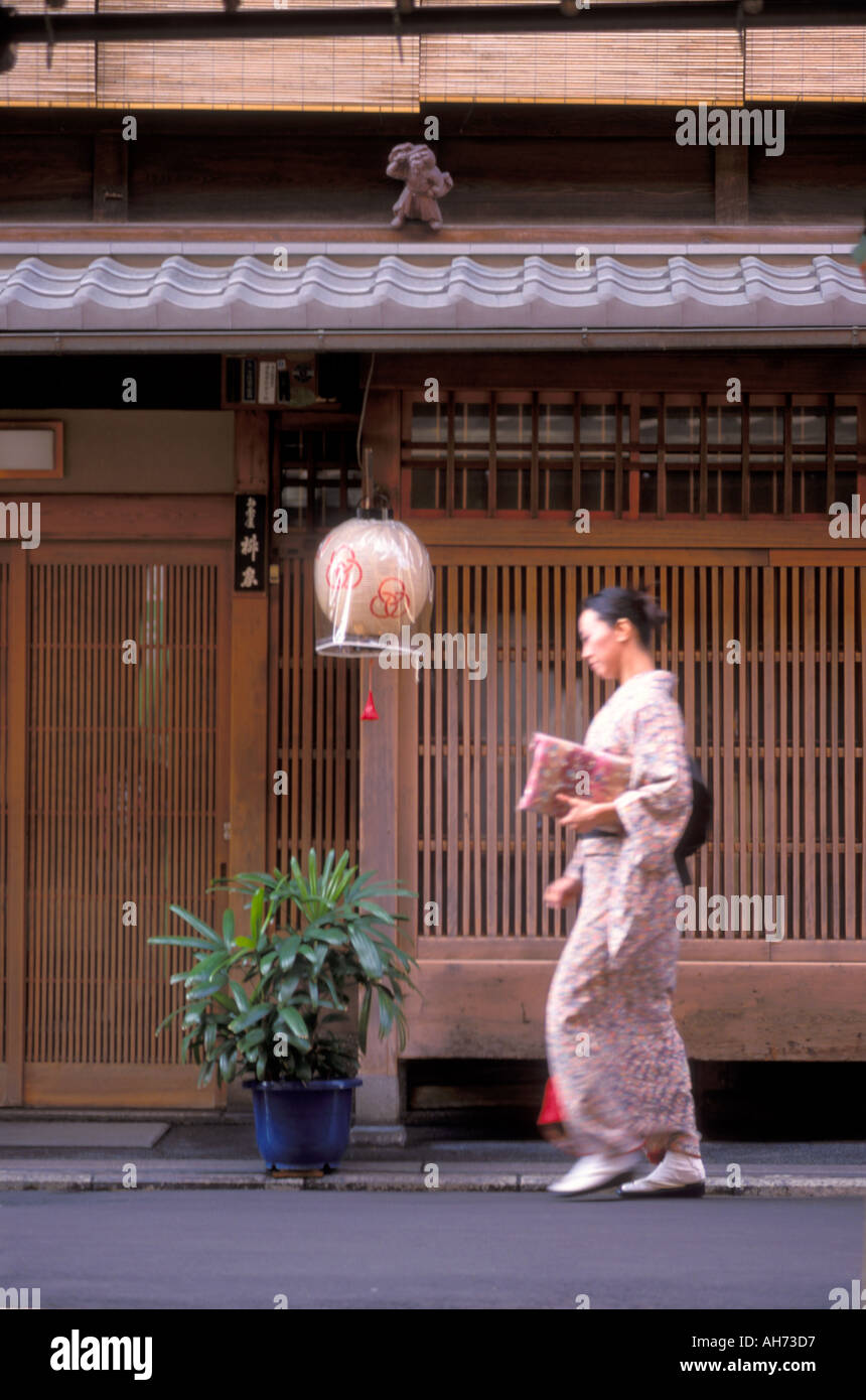 Une maiko, apprentie geisha, ou sans maquillage flânant passé un machiya ou maison de ville, sur une rue de Kyoto Banque D'Images