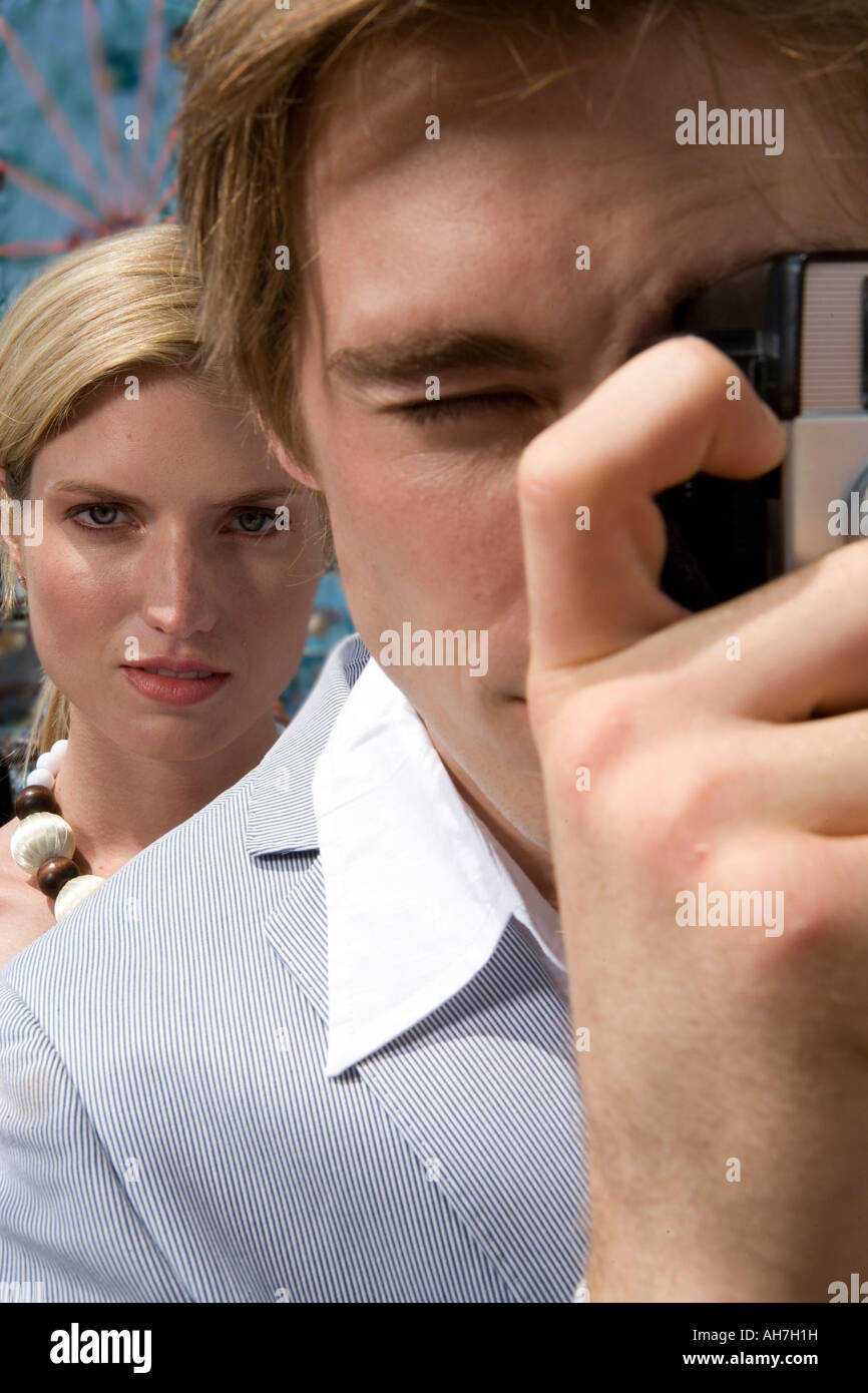 Close-up of a young faire prendre une photo avec une jeune femme derrière lui Banque D'Images