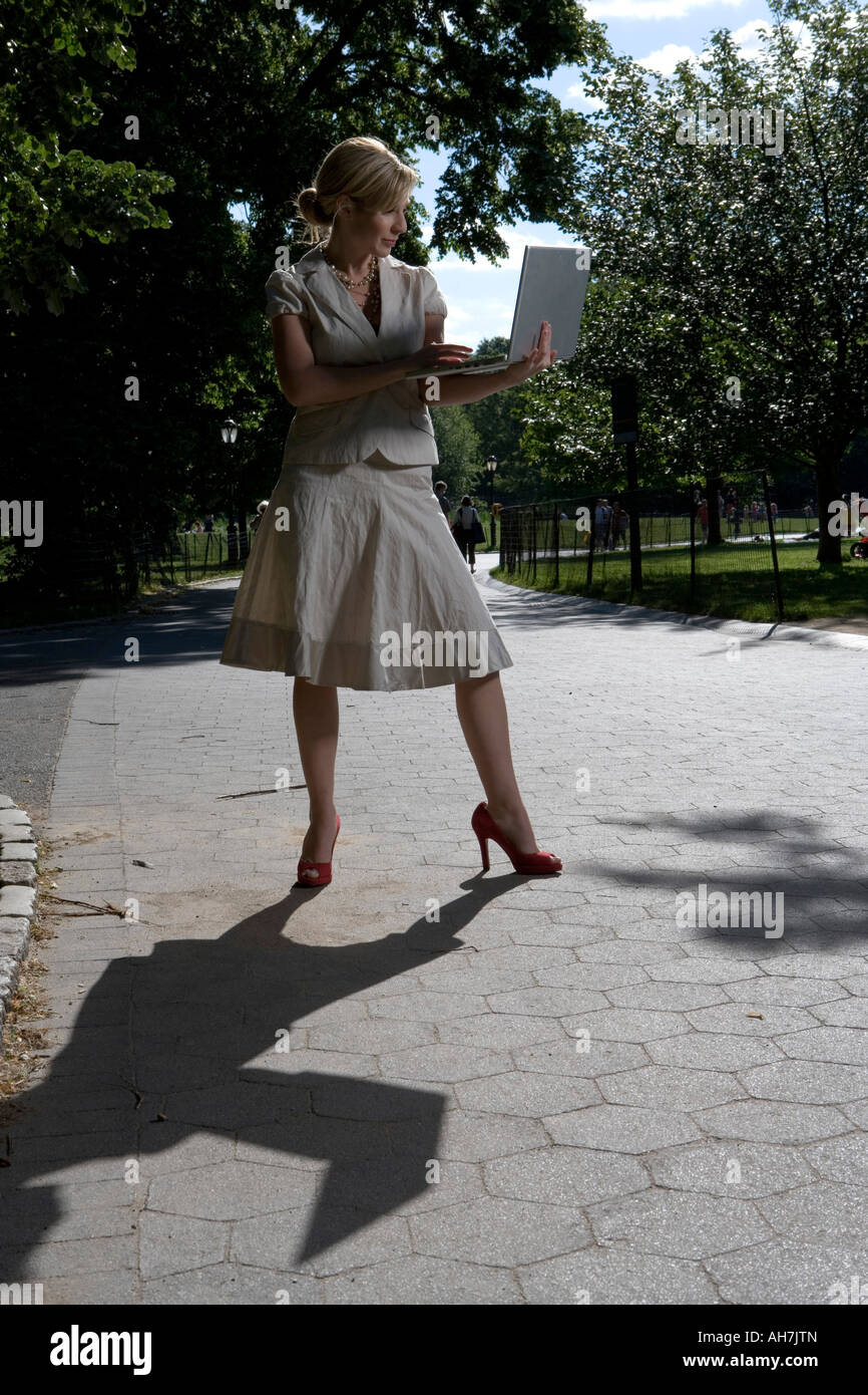 Jeune femme à l'aide d'un ordinateur portable et debout sur un chemin Banque D'Images