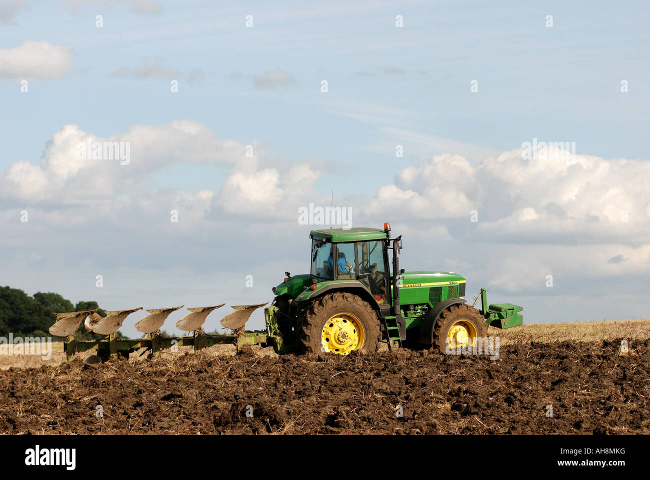 Tracteur John Deere à labourer le champ de chaume, Warwickshire, England, UK Banque D'Images