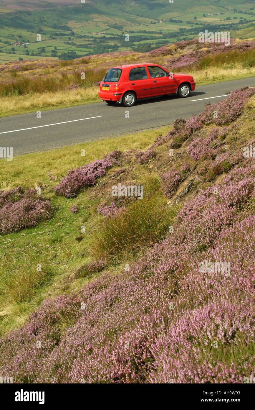 Voiture rouge dans la région de North Yorks heather National Parc couvert Yorkshire Banque D'Images