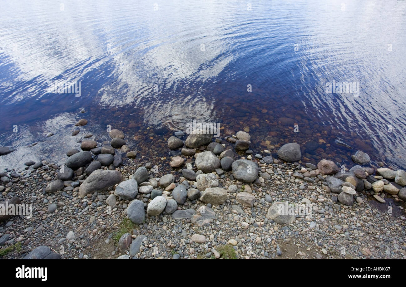 À partir de la surface de l'eau reflétant le ciel et des pierres au Lakeshore Banque D'Images