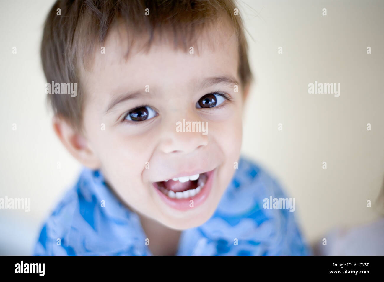 Mignon petit garçon aux cheveux brun regarde l'appareil photo tout en ricanant et avec un petit rire Banque D'Images