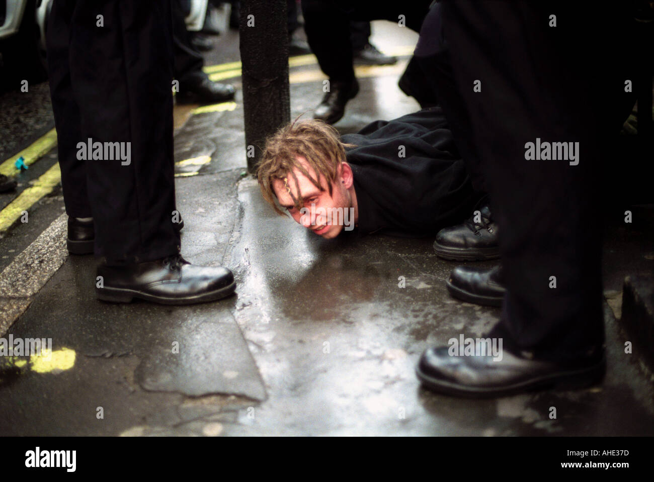 Les jeunes manifestant renversé par la police menotté et maintenu au sol par la police lors des manifestations de détresse au centre de Londres. Banque D'Images
