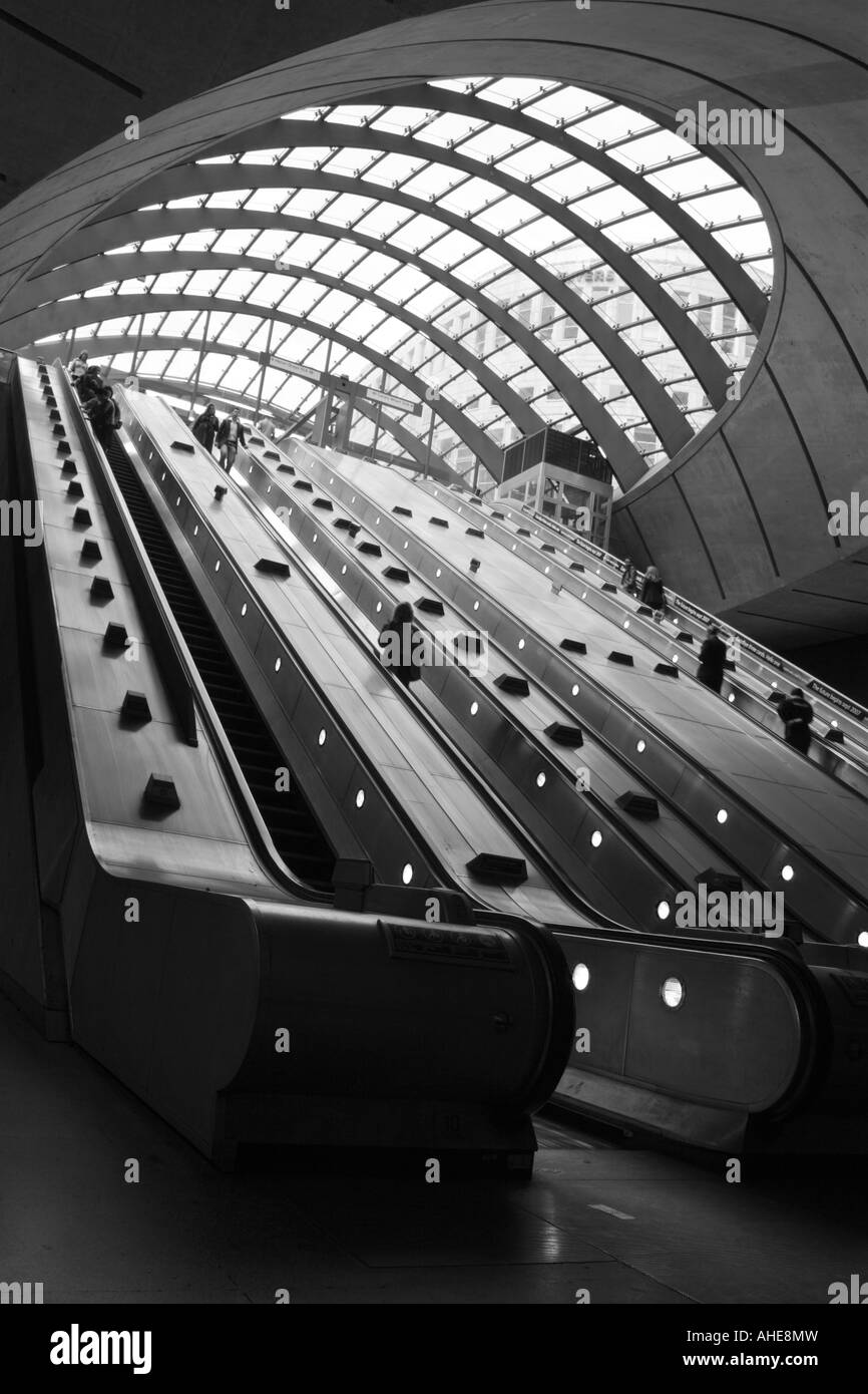 Photographie en noir et blanc des navetteurs sur les escaliers mécaniques à la station de métro Canary Wharf, les Docklands, Londres, Angleterre Banque D'Images