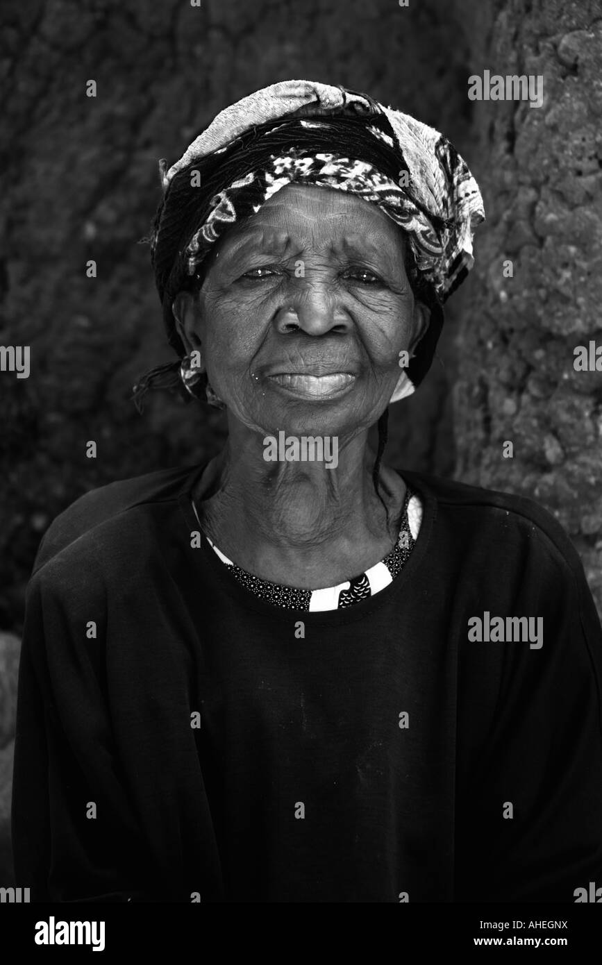 Senior African woman avec la tête enveloppée d'écharpe du regard et d'étudier. Banque D'Images