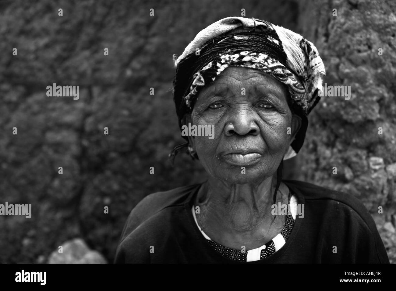 Senior African woman avec la tête enveloppée d'écharpe du regard et d'étudier. Banque D'Images