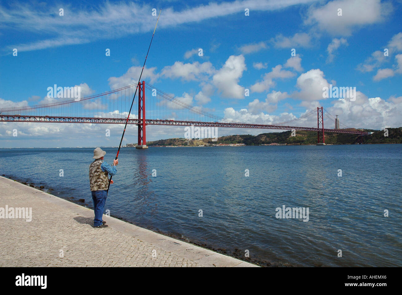 L'homme pêche avec une canne à pêche près de la rivière Tagus pont ou pont du 25 avril (Ponte 25 de Abril) à Lisbonne, Portugal Banque D'Images