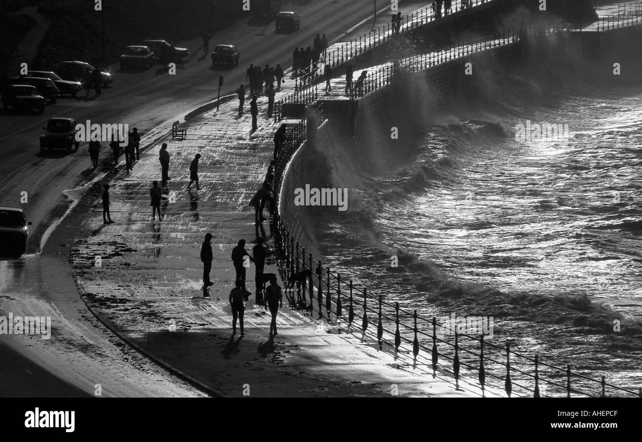 Les gens silhouette sur l'eau lumineuse qui avait éclaboussé le relais de la mer, sur la route Banque D'Images