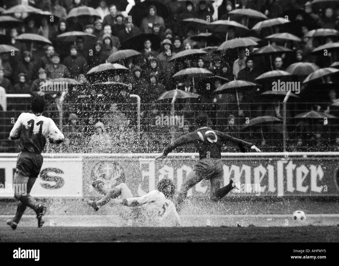 Football, Bundesliga, 1971/1972, Niederrhein Stadium à Oberhausen, le poste d'Oberhausen contre le FC Schalke 04 2:3, un temps pluvieux, jeu dans de fortes pluies, les spectateurs et fans de football avec parasols, scène du match, Uwe Kliemann, RWO (5) dans une flaque d'eau Banque D'Images