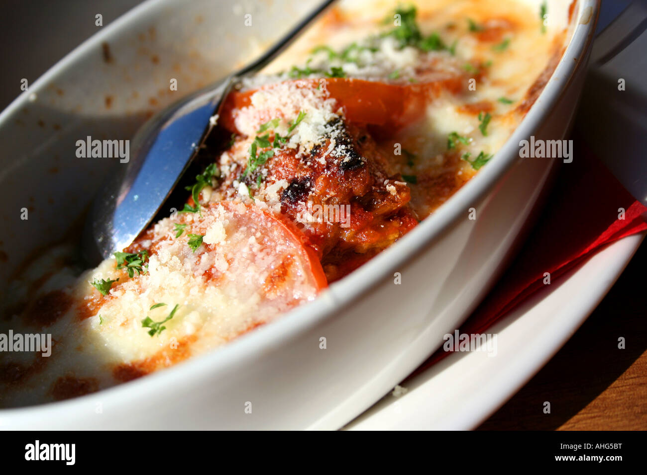 Melanzane alla parmigiana avec aubergine grillée, tomates, mozzarella, parmesan cuit au four et persil frais dans un plat blanc. Banque D'Images