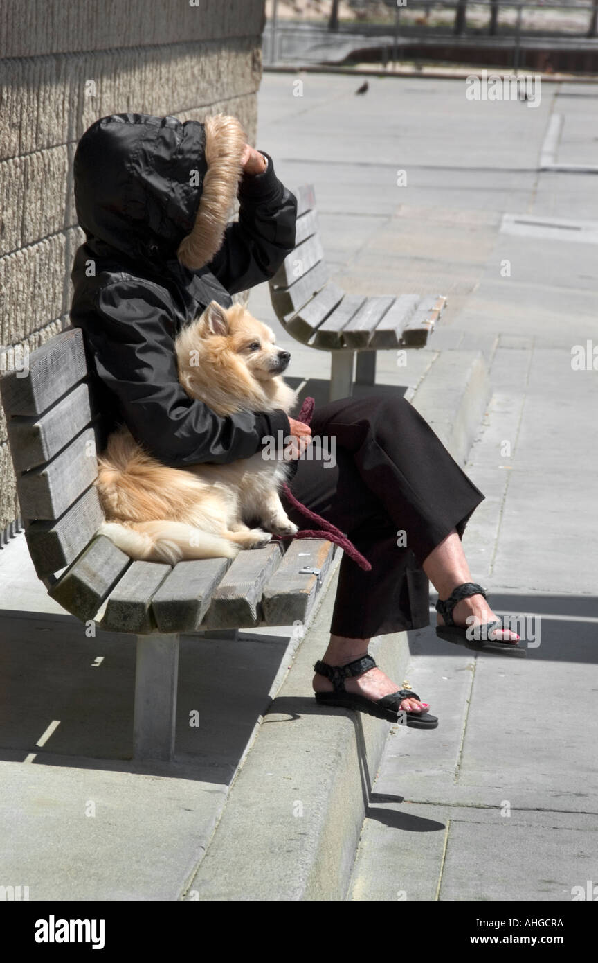 Awoman avec col de fourrure d'un animal capot on retrouve sur un banc avec son bras autour de son chien de compagnie Banque D'Images