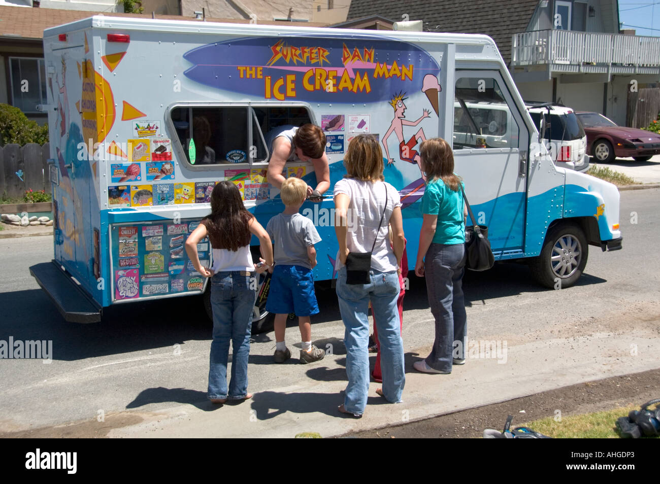 Un camion de crème glacée s'arrête dans un quartier pour vendre les produits laitiers candy traite de la famille et leurs amis. Banque D'Images