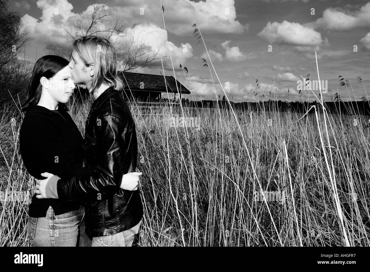 Un couple s'embrasser sur un lac romantique avec ciel nuages et Reed dans l'arrière-plan Banque D'Images