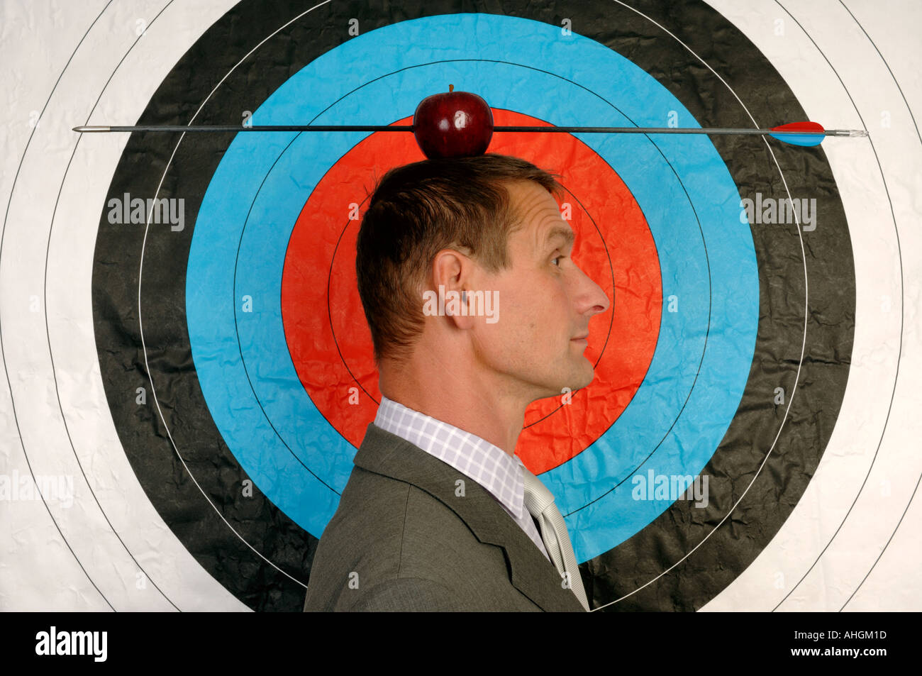 Businessman en face d'une cible avec une pomme et flèche sur la tête Banque D'Images