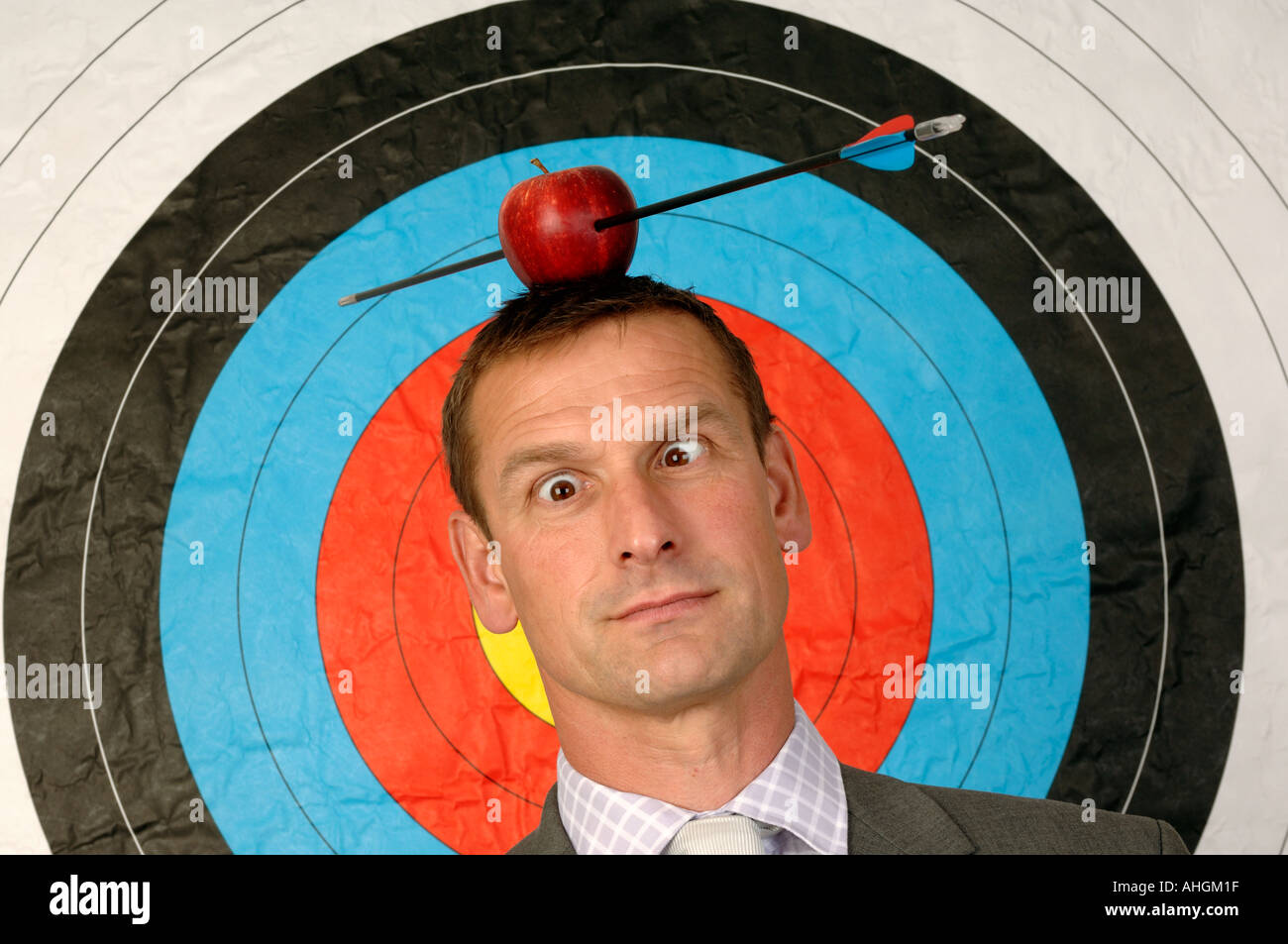 Businessman en face d'une cible avec une pomme et flèche sur la tête Banque D'Images