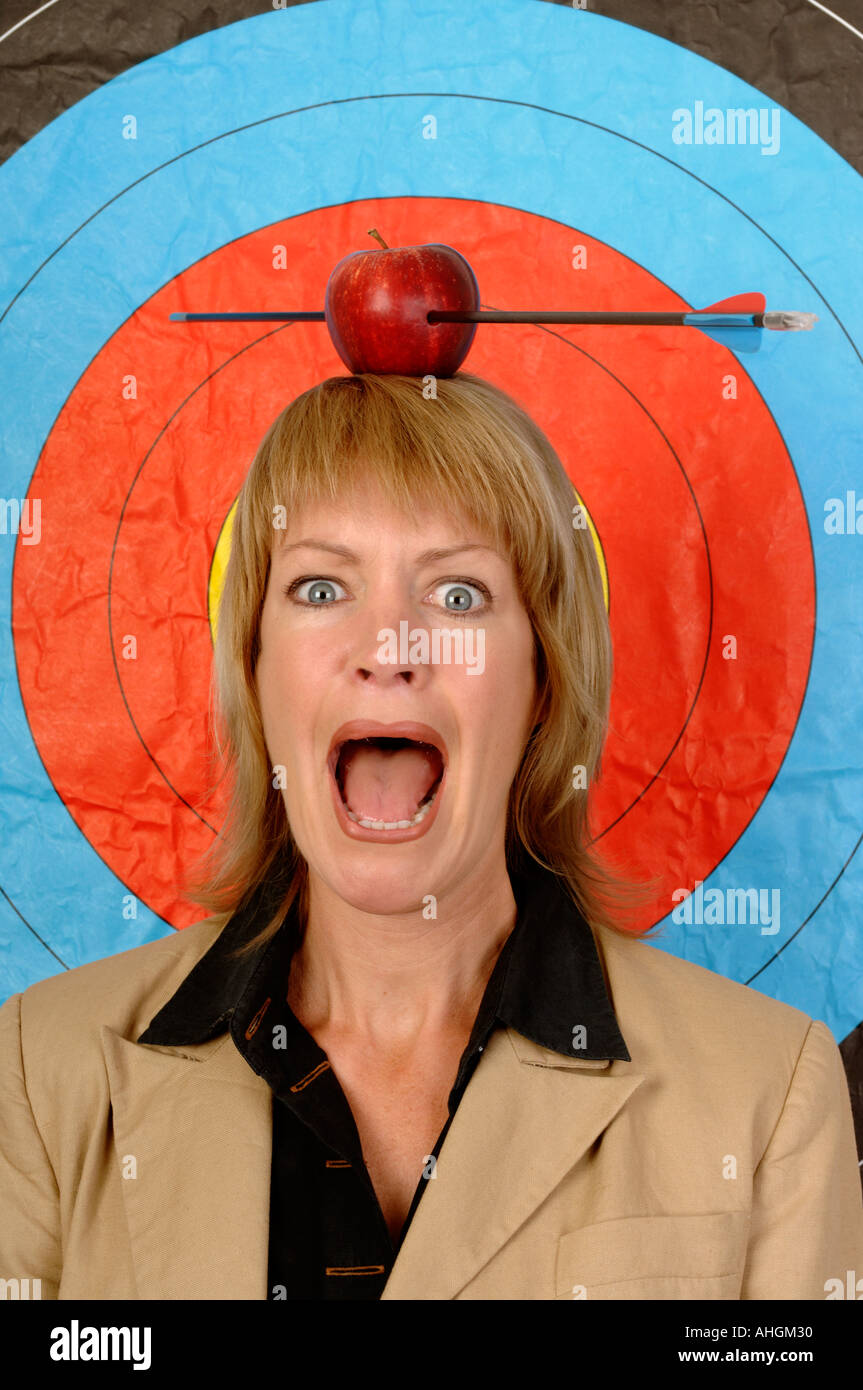 Businesswoman in front of une cible avec une pomme et la flèche sur la tête. Banque D'Images