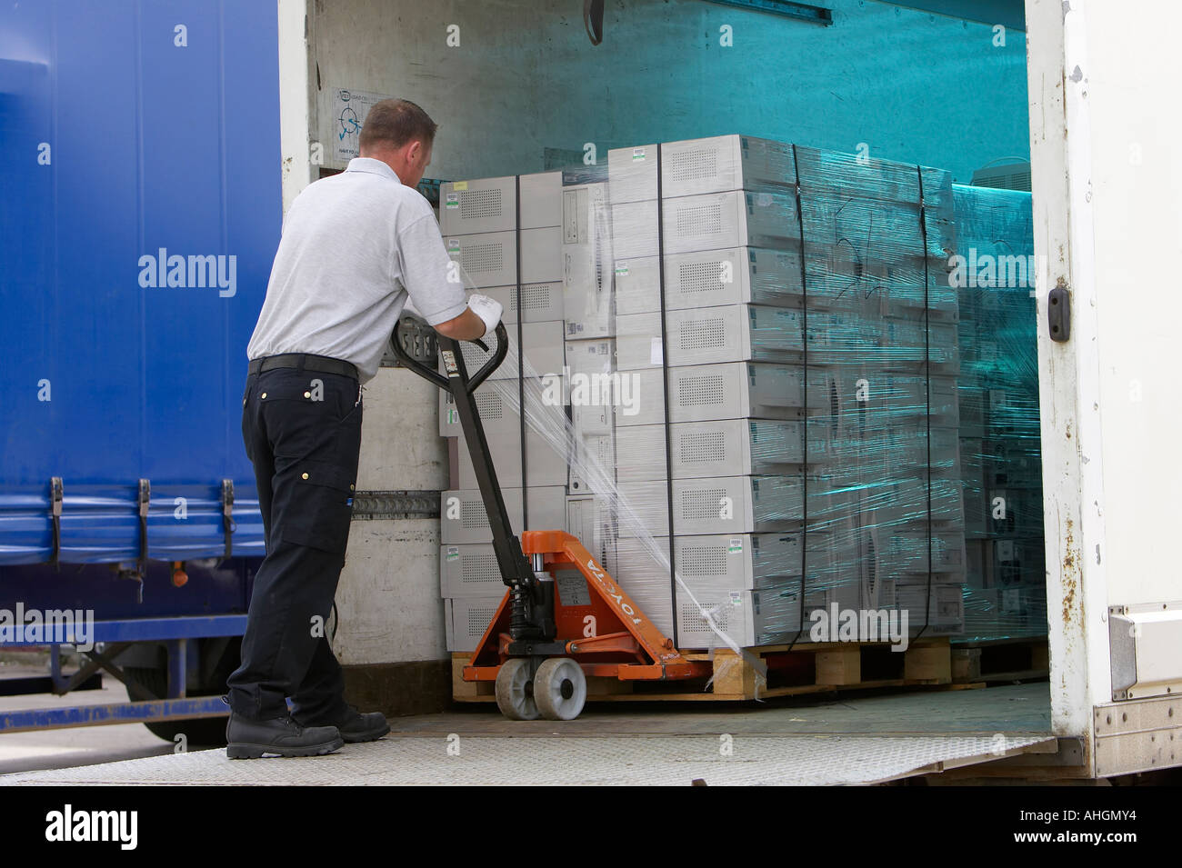 Ouvriers déchargement camion plateau élévateur contenant palette enveloppée des piles de boîtes de système informatique pour le nettoyage des données et de recyclage Banque D'Images