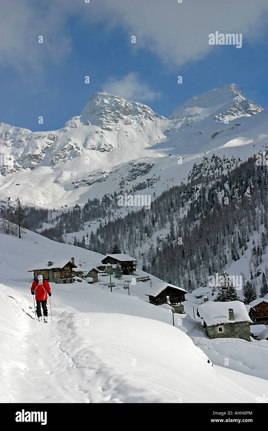 Trudging skieur d'âge moyen d'une légère pente dans la neige profonde sur une colline dans la région de la vallée de Champoluc d Aoste Italie Banque D'Images