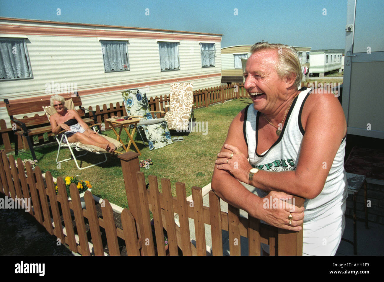 Senior couple relaxing in the Sun en dehors de leur caravane statique à Porthcawl Trecco Bay South Wales UK Banque D'Images