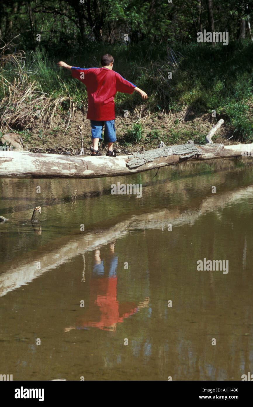 Boy crossing Creek on Log Banque D'Images