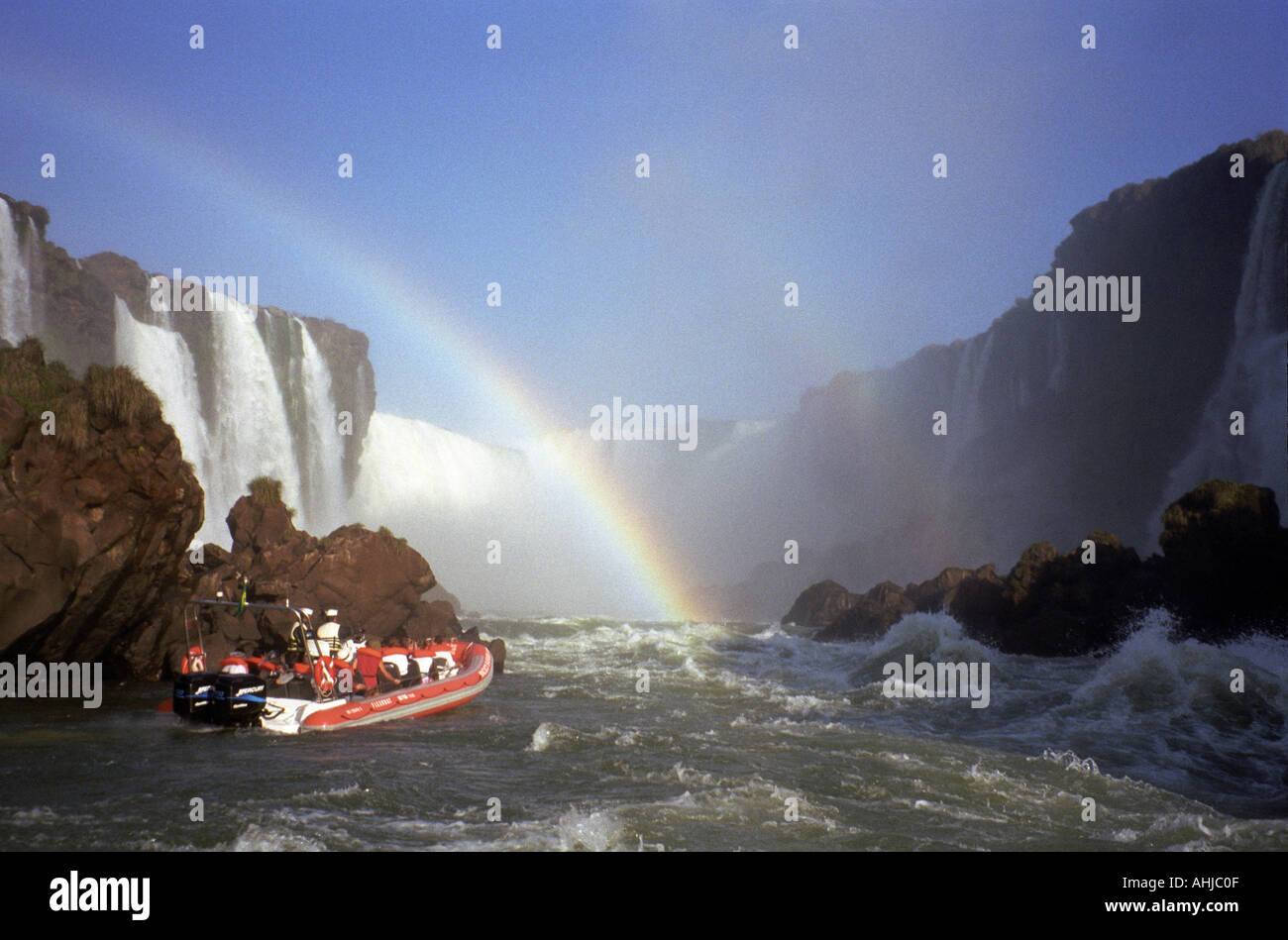 Bateau d'excursion rouge et blanc rempli de touristes à l'entrée de la section de la gorge des Devils des chutes d'Iguaçu avec arc-en-ciel au-dessus. Etat de Parana, Brésil. Banque D'Images