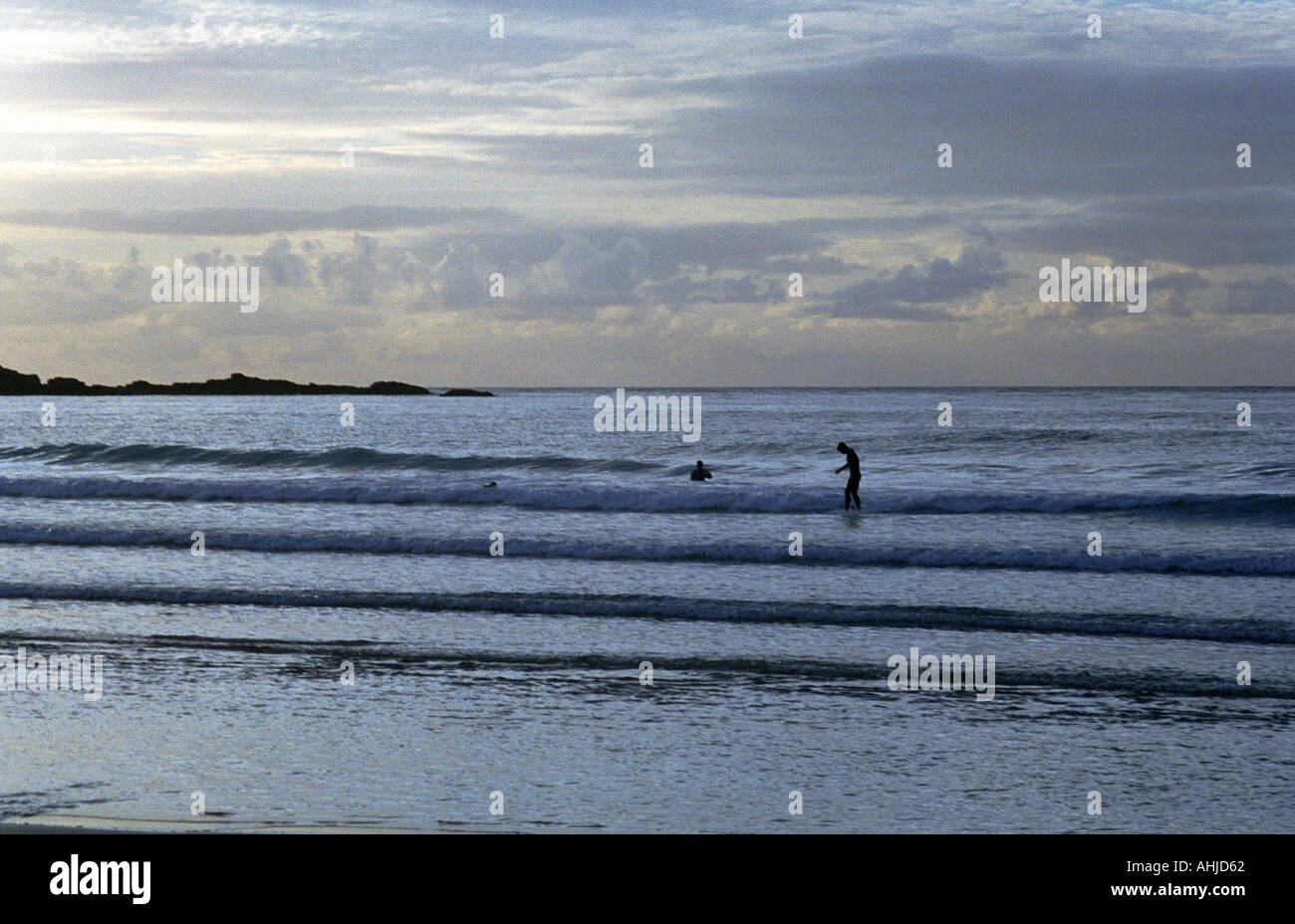 Deux personnes dans le surf à la plage de Porthmeor sous un ciel couvert. St. Ives, Cornwall, Royaume-Uni. Banque D'Images